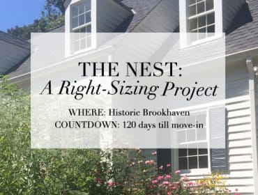Exterior of a white house with gray roof, dormer windows, and lush greenery. Text overlay reads "THE NEST: A Right-Sizing Project WHERE: Historic Brookhaven COUNTDOWN: 120 days till move-in."