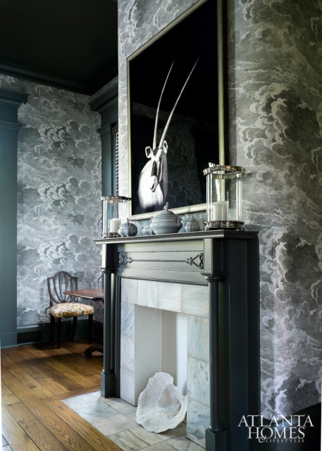 With moody artwork above its marble-clad mantel and an almost ominous Fornasetti wallpaper, the dining room takes on a dramatically different countenance than its former, more formal predecessor.