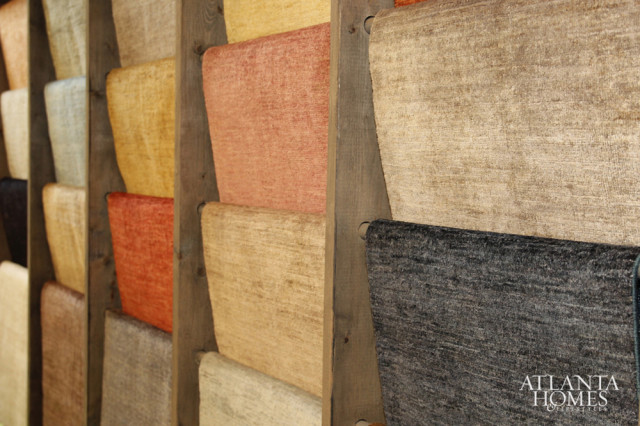 Swatches of textured fabric in various colors including cream, tan, rust, yellow, and charcoal gray displayed on wooden shelves.