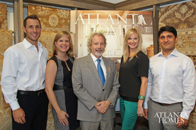 Five people posing for a photo in front of a backdrop featuring the Atlanta Homes & Lifestyles logo and kitchen imagery. The individuals are dressed in business casual attire.