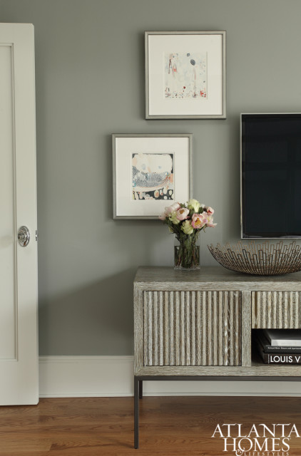 Gray living room with a light wood console table featuring fluted doors, a glass vase of peonies, abstract art, and a decorative metal bowl.