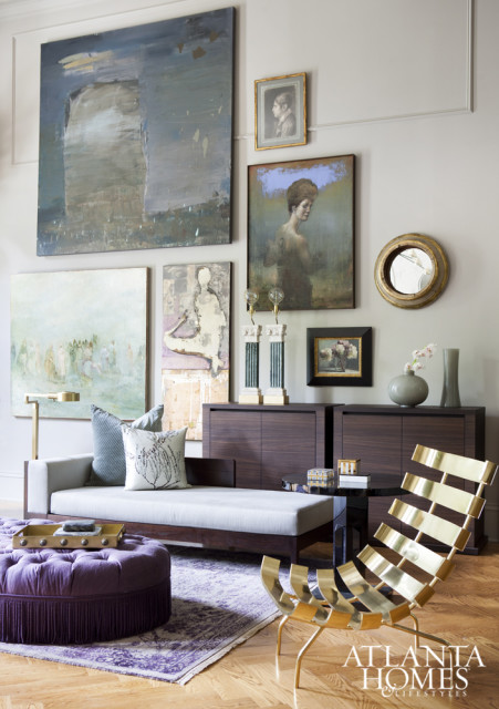 Living room with a light gray chaise lounge, purple tufted ottoman, abstract art, and a gold slatted chair.