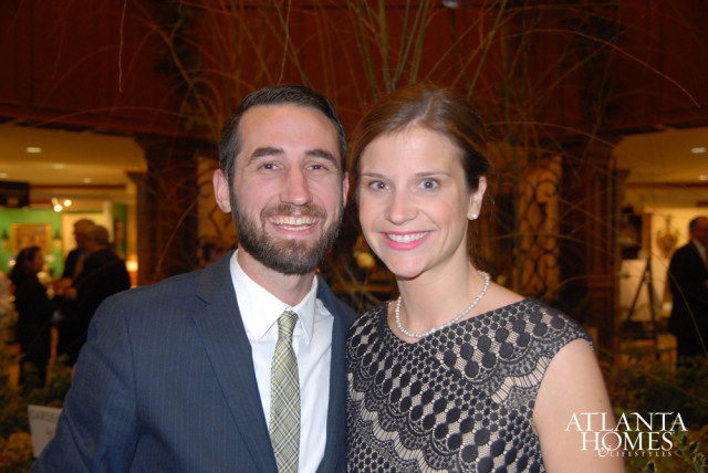Man in a pinstripe suit and green plaid tie smiles next to a woman in a black lace dress and pearl necklace. Atlanta Homes & Lifestyles logo is visible in the lower right.
