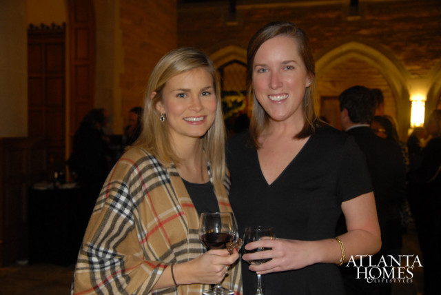 Two women smiling, one wearing a plaid shawl and the other a black dress, holding glasses of red wine. The Atlanta Homes & Lifestyles logo is visible in the lower right corner.