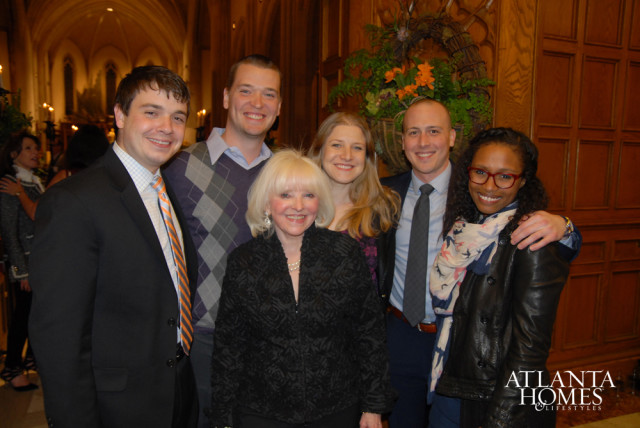 Group of six people posing for a photo in a room with wood-paneled walls and arched ceilings. The Atlanta Homes & Lifestyles logo is visible in the bottom right corner.