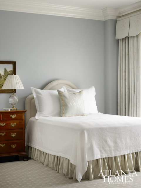 Pale blue adds a soothing touch in the guest bedroom, where a geometric side table from Huff Harrington injects a modern touch to the traditional room. Chair fabric by Kravet.
