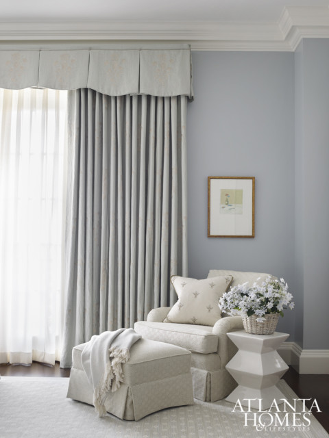 Pale blue adds a soothing touch in the guest bedroom, where a geometric side table from Huff Harrington injects a modern touch to the traditional room. Chair fabric by Kravet.
