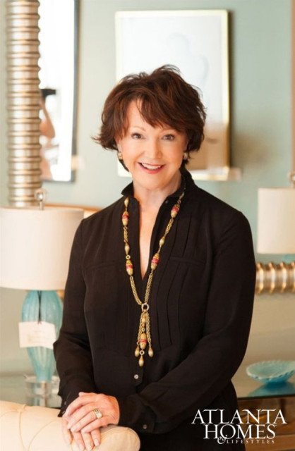 Woman with short brown hair wearing a black blouse and a long gold necklace with pink and gold beads. She is smiling and wearing rings on her left hand. The Atlanta Homes & Lifestyles logo is in the lower right corner.