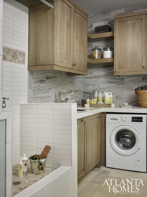 The laundry room contrasts with the mudroom’s light-filled design scheme. French limestone flooring, also a smart choice for lakeside wear-and-tear, seamlessly ties both spaces together.