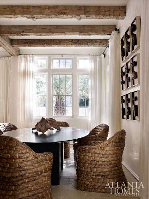 In the adjacent dining area, raffia chairs purchased at High Point Market sidle up to a Julian Chichester tabletop with a custom base. Turner also commissioned the mounted wood-block artwork from Soicher Marin.