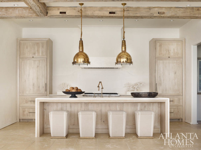 Antique light fixtures, a Venetian plaster hood and Lee Industries stools lend the sleek kitchen a calming effect.
