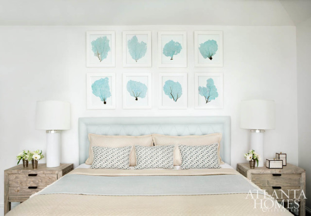 Shades of blue and sandy taupe keep the mood cool and calm in the ocean suite. The custom linen headboard is accented by throw pillows from Bungalow Classic and bedding from Gramercy Home. The bedside tables are from Bungalow Classic. Lamps are from Visual Comfort, and artwork is from Wendover Art Group.