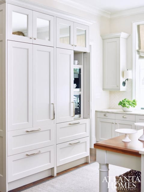 White kitchen with custom cabinetry, mirrored upper cabinet doors, built-in coffee maker and microwave, and brushed nickel hardware.