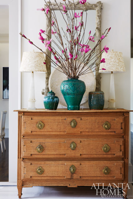 The entry foyer mixes rustic with formal touches thanks to a textured mirror and antique chest, both from The Stalls.