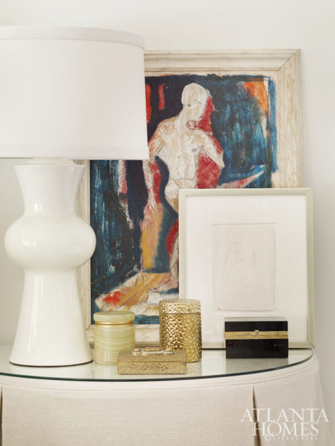 A bedside table features a sculptural Arteriors lamp and an antique painting.