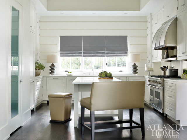 A custom concrete console by Bradley doubles as a bar in the dining area. Turner outfitted the kitchen with seating from Lee Industries to offer a casual alternative for dinnertime. The lamps are from Bungalow Classic.