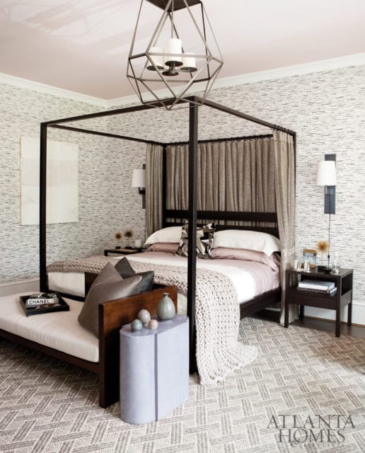 Bedroom with a dark wood four-poster bed, textured wallpaper, a geometric chandelier, and a light purple side table.