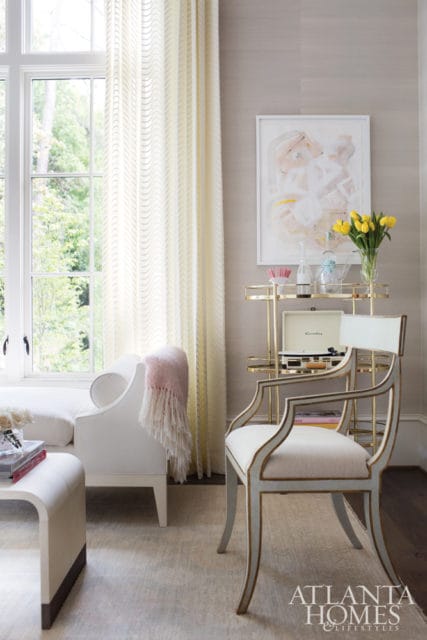 Living room with a white sofa, a light blue and gold accent chair, a gold bar cart with a record player, and abstract art on a textured wall.
