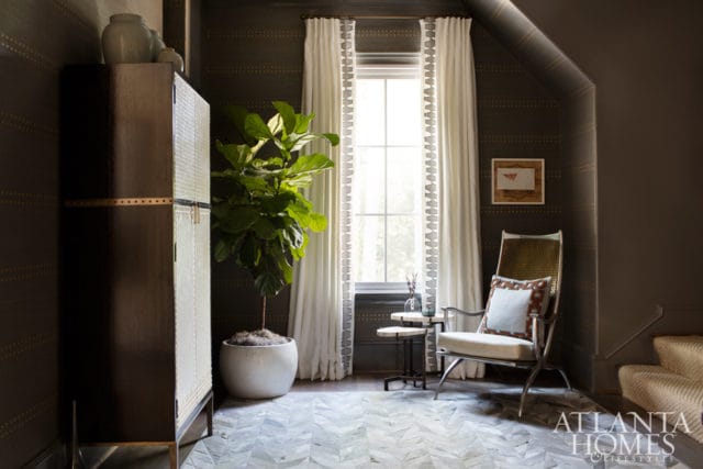 Dark wallpaper with gold dot pattern, tall window with white curtains, a metal chair with patterned cushion, and a tall cabinet with a fiddle leaf fig plant.
