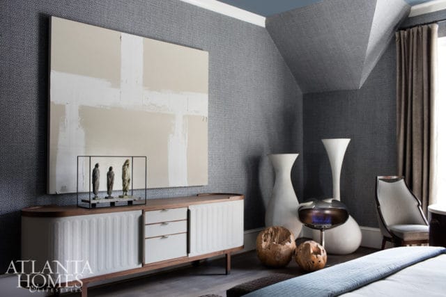 Bedroom with gray textured wallpaper, a large abstract painting, a white credenza with sculptures, and two tall white vases.