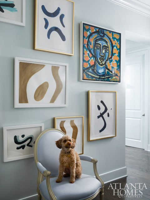 A gallery wall by the entryway includes a portrait by America Martin and abstracts by Brian Carter.