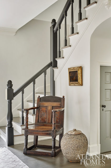 In the entry foyer, a carved French chair—one of Debbie’s first purchases when she moved into the house more than 30 years ago—comingles with an African jar and oil on canvas.