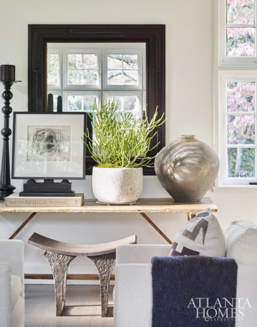 A rustic-chic focal point in the living room includes an antique trestle table, an iron stand and candelabra from Townhouse by Robert Brown and pottery from B.D. Jeffries.
