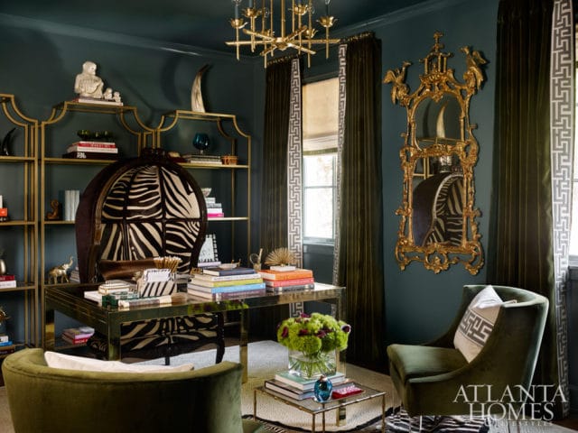 Dark teal office with gold shelving, a zebra print chair, a gold ornate mirror, and a brass desk