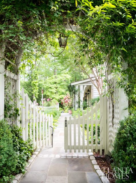 A white picket fence and arbor are accented by vines of Carolina Jessamine and an antique iron lantern found at a market in Provence.