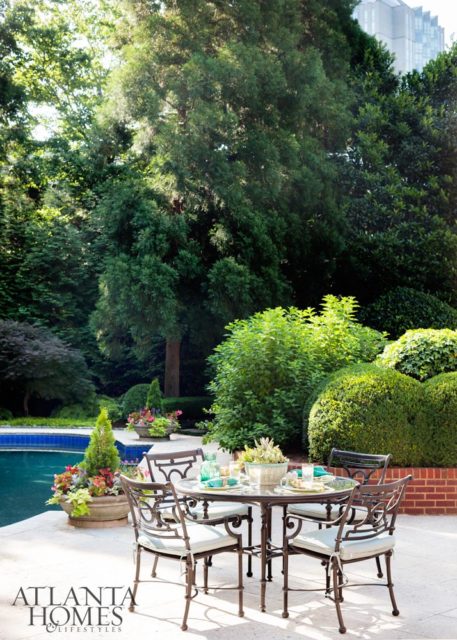 A lush, mature landscape gives the outdoor living spaces great privacy. Large stone planters sit at each pool corner, each filled with a topiary surrounded by a variety of seasonal plants.