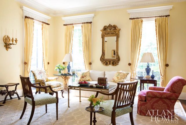 “I wanted the living room to feel bright and to come alive,” says homeowner John Banks. Soft-hued walls, a sisal rug, wooden armchairs, a pretty floral pattern and touches of blue and white contribute to the comfortably elegant feel.