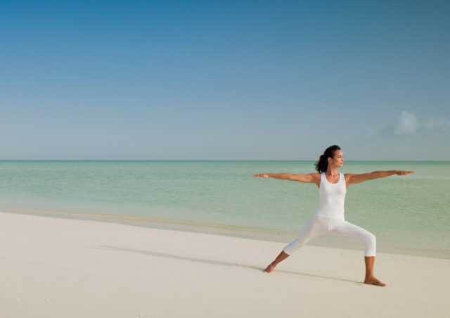 The white beach and calm crystal sea makes a perfect backdrop for yoga.