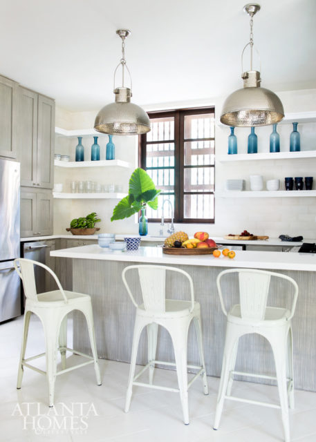 Custom limewashed cabinets paiir with Caesarstone countertops, Company pendants and open shelving for beach-chic appeal.