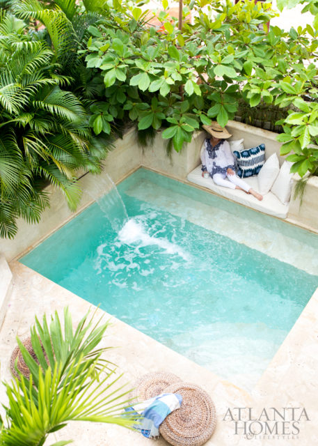 Interior designer Beth Webb indulges in respite on the plunge pool sun shelf, where a Sunbrella cushion and Madeline Weinrib pillows provide punchy comfort.