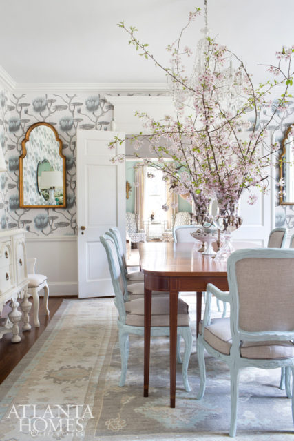 in the dining room, a colorful Oushak rug picks up the color thread of the large-scale wallpaper and painted chairs.