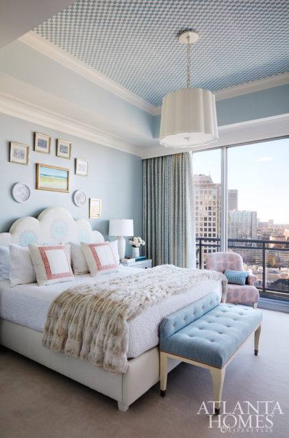 The master bedroom’s atmosphere has hints of glamour that spring from the velvet coverlet, faux-fur throw and custom wallpaper on the ceiling by Stephen Floyd Design.