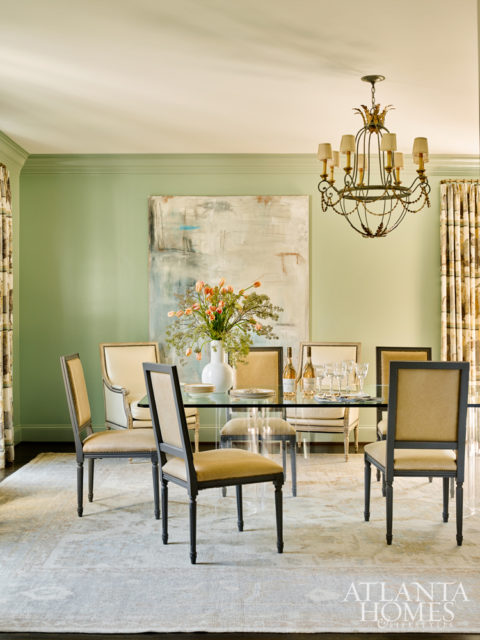 The sunlit dining room of this Argonne Forest home is transitional in tone, softening the space’s slightly more old-fashioned purpose. Here, a glass-and-Lucite dining table reflects more light than a traditional wood one would, and an oversize abstract expressionist canvas by Hutton Snellings adds personality.