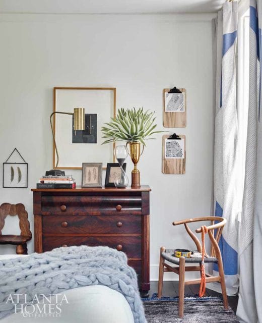 Bedroom with a dark wood dresser topped with books, a lamp, and a plant. A wooden chair with a dog collar and leash sits nearby.