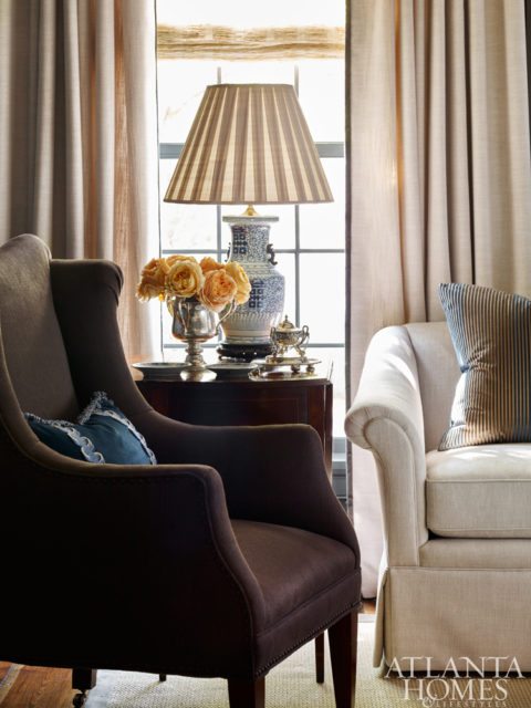 The living room-cum-study is moody but mindful. Collectively, its dark walls, bold brass and symmetrical sightline almost recall the well-mannered glamour of Dorothy Draper’s Victorian Writing Room at the Greenbrier Hotel. Even the handsome card table could easily sub as a writing desk.