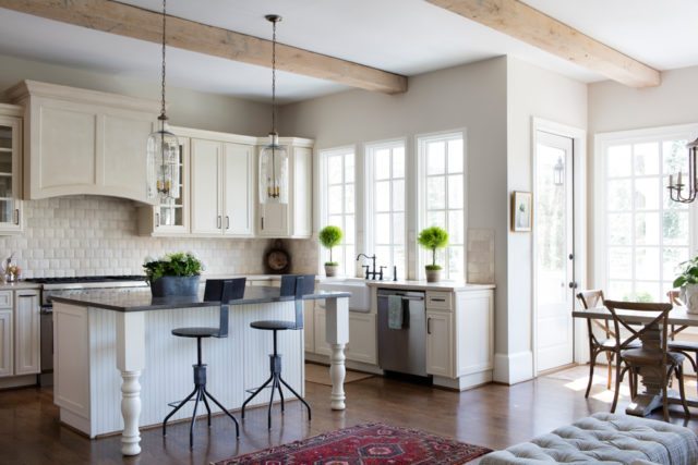 The kitchen is a classic creamy white with glass-front cabinets; beams with a whitewash finish bring another layer of texture.