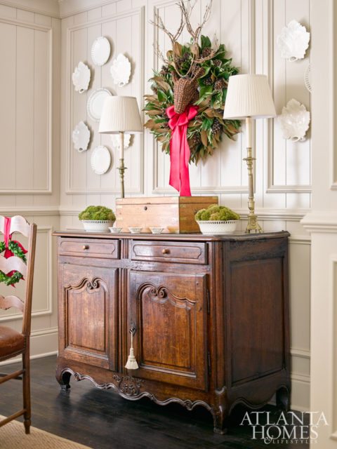 The pinecone-petal deer with twig antlers is perched above the chest year-round; here, a festive wreath by Le Jardin Français creates a focal point.