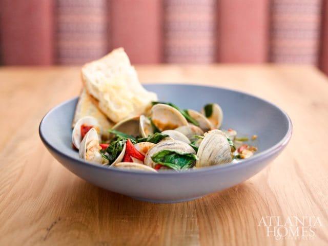 Bowl of clams with spinach, red peppers, and toasted bread, with Atlanta Homes & Lifestyles logo in the lower right corner.