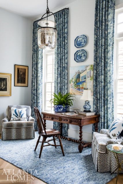 Study with a dark wood desk, ornate chair, leopard print armchair, and blue floral curtains. A blue and white rug covers the floor.