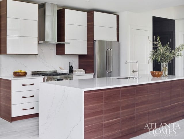 Modern kitchen with white high-gloss cabinets, dark wood lower cabinets and island, stainless steel appliances, and white quartz countertops.