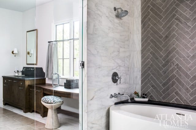 Bathroom with white marble subway tile shower, gray herringbone tile accent wall, freestanding tub, and dark wood vanity with stone countertop.