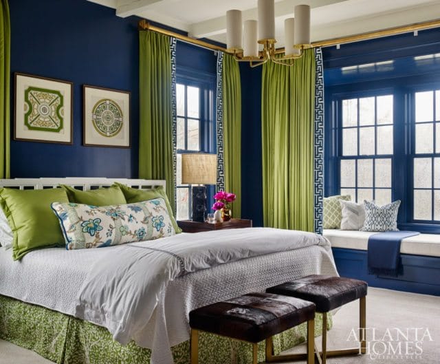 Bedroom with navy blue walls, lime green curtains, a white bed with green and floral pillows, and a window seat with blue cushions.