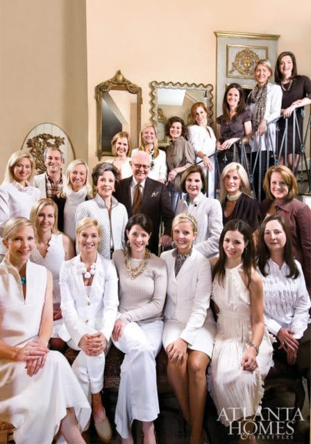 Group portrait of people posing on and around a staircase, with a man in a suit and several women in dresses and suits.