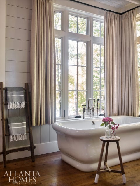 Function meets style in the master bath where Westbrook used trimwork to combine medicine cabinets and an interior window into one cohesive unit. The vanity is by Morgan Creek Cabinet Company. A soaking tub also adds a hint of luxury to laid-back lake life.