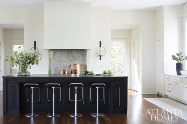 Shiplap wall paneling conceals the refrigerator and range hood in the spacious kitchen, which has perimeter cabinets with quartzite countertops and an island with granite countertops.