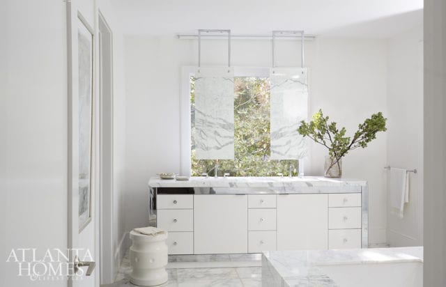 In the master bathroom, a pair of mirrors fabricated by Kevin Grisso of Custom Artisan Group have been suspended from the ceiling above a white vanity with chrome detailing.